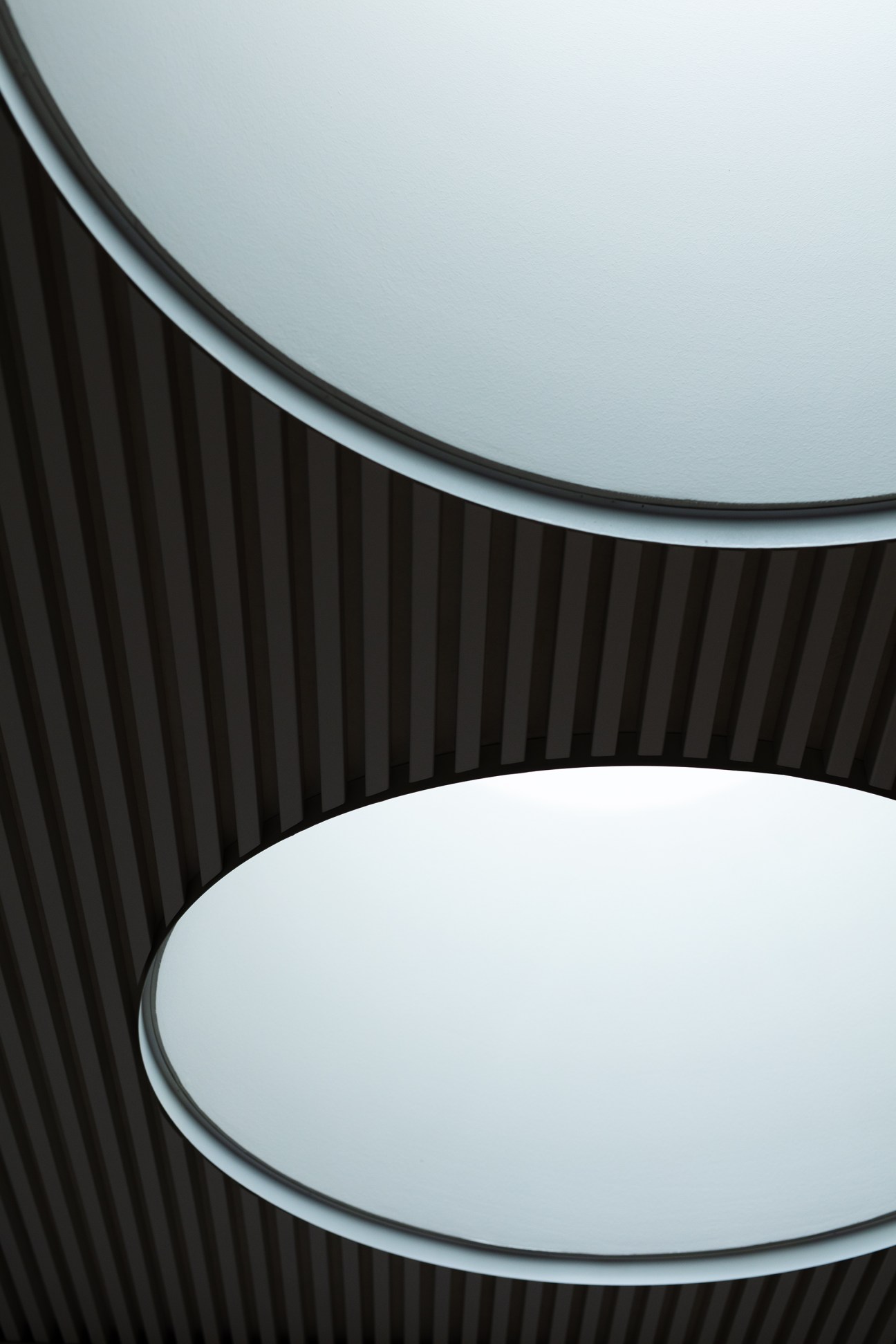 Circular lights mounted on a dark ribbed ceiling at the Alvar Aalto-designed Engineer House