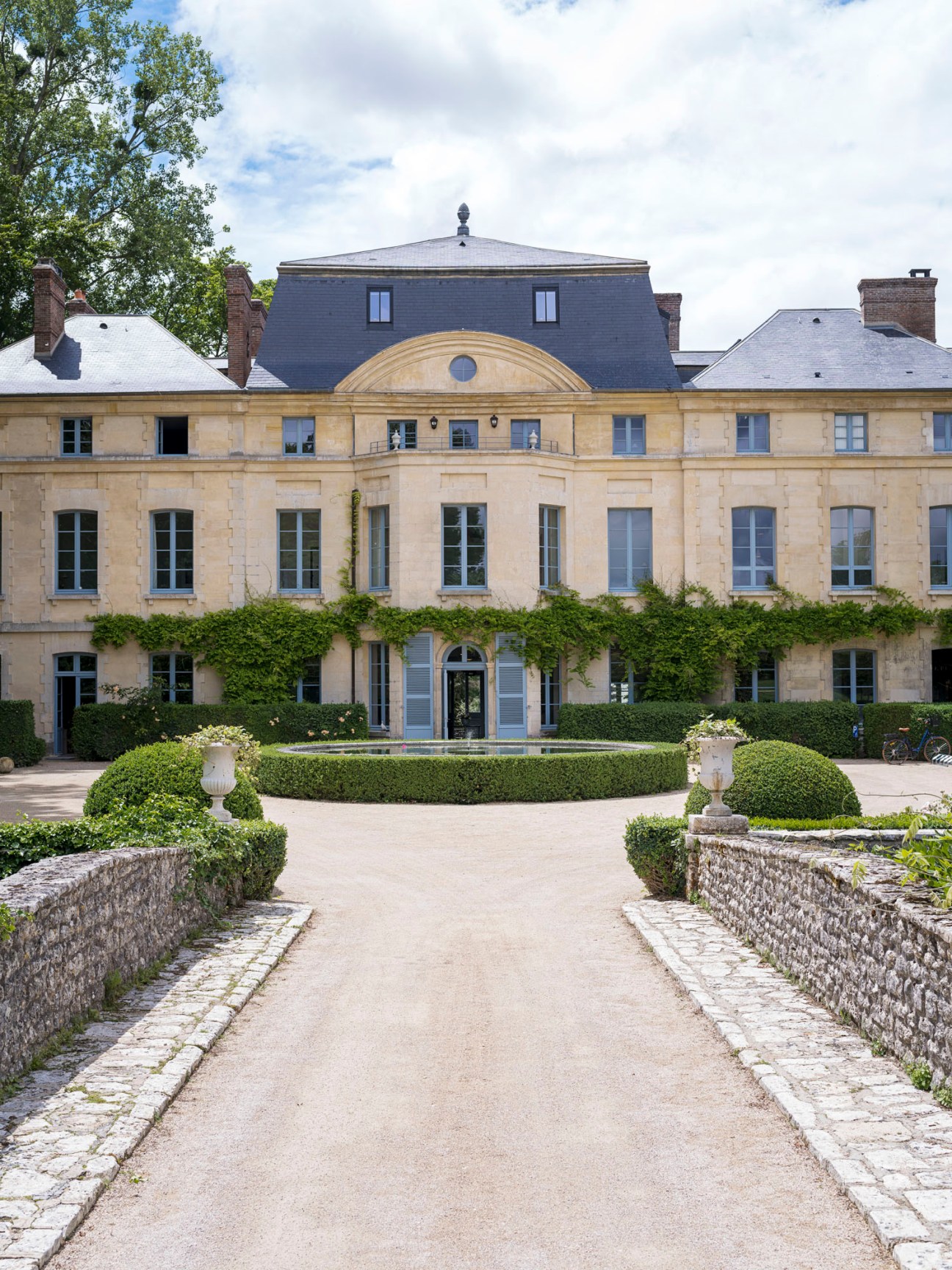 Imposing 18th-century château with ivy-covered walls set in landscaped gardens