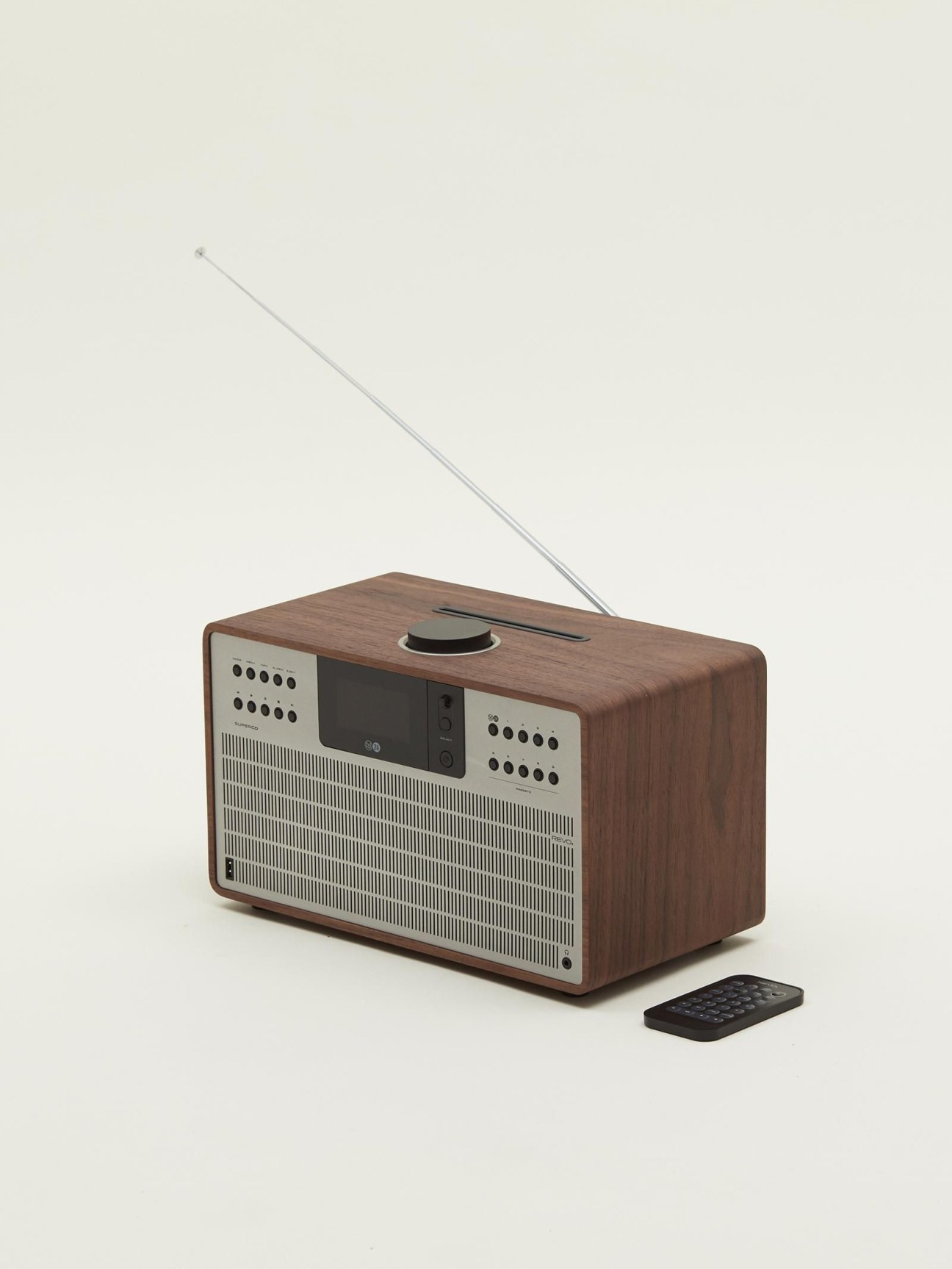 Wooden radio with silver metal grille, telescopic antenna, digital display, and remote control on neutral background