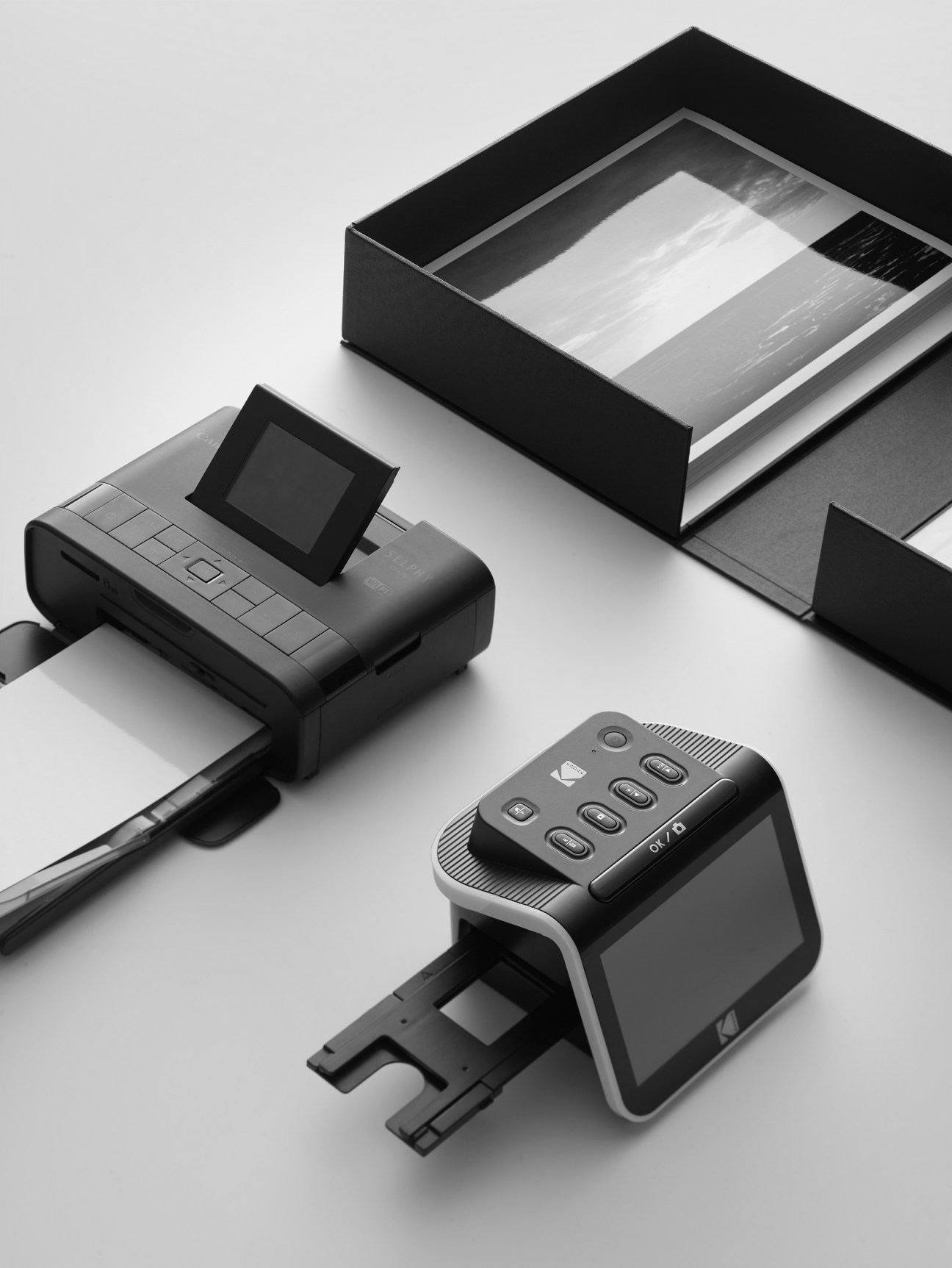 Photo scanning equipment and archive supplies arranged on white surface including printer and storage box
