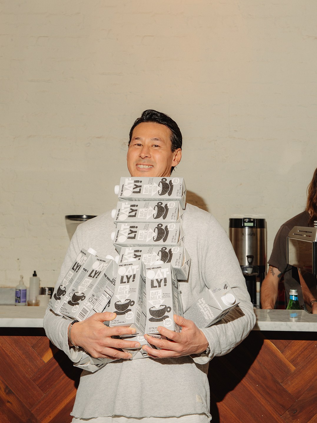 Toni Petersson holding stacks of Oatly oat milk cartons with distinctive packaging