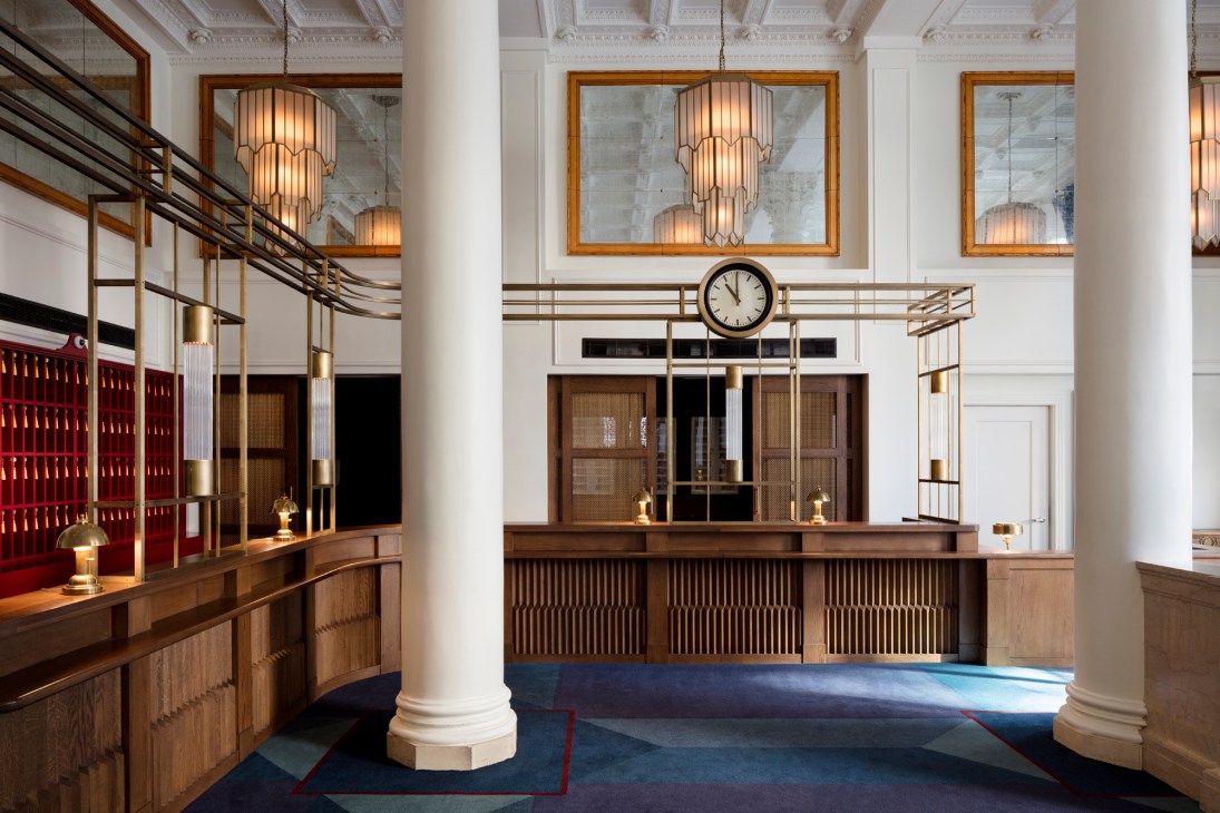 Grand lobby reception area of Riggs hotel in Washington DC with wooden counters, art deco chandeliers, and classical architecture.