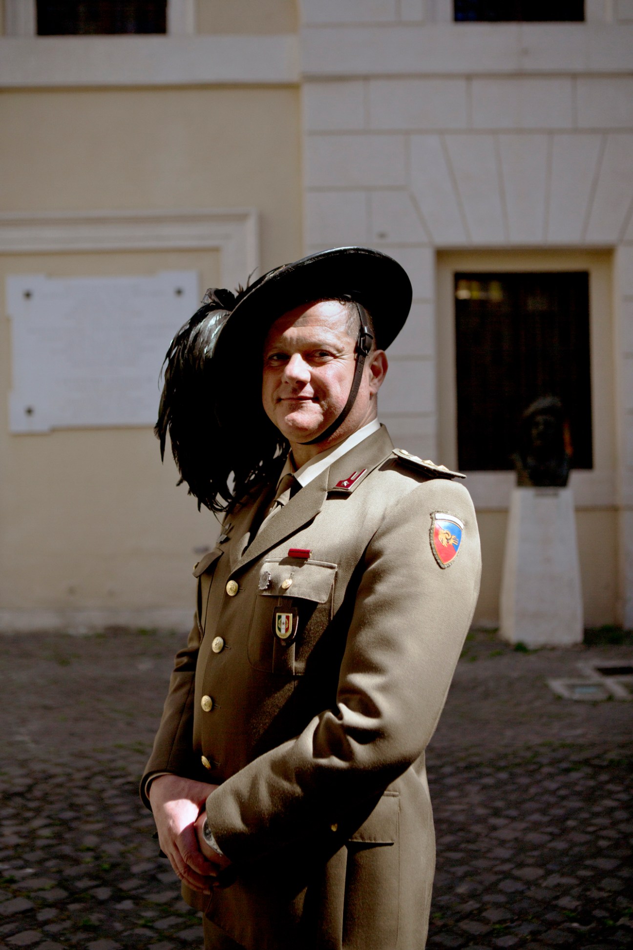 Italian police officer in beige uniform with black feathered hat standing in courtyard