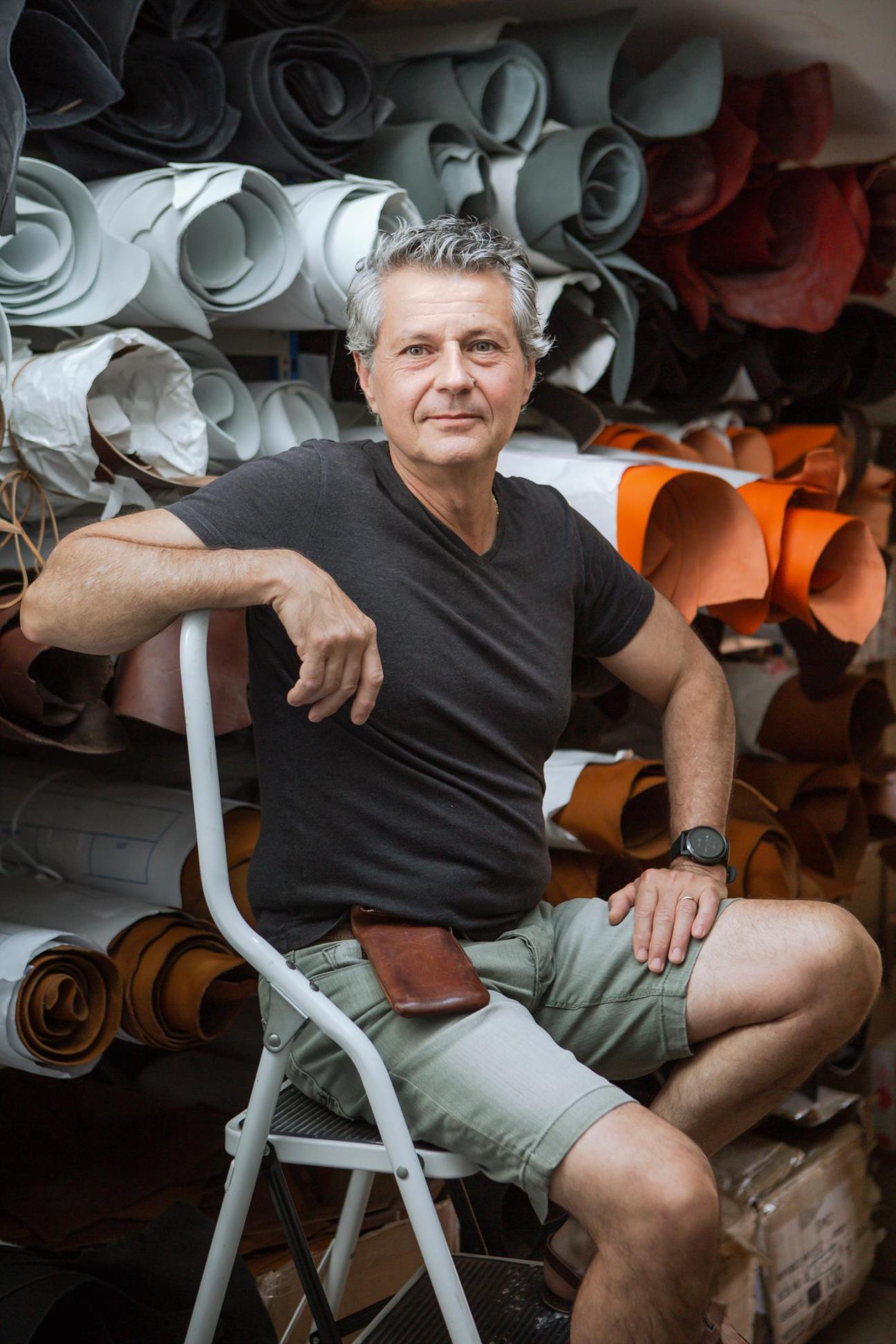Alain Rondini, owner of the Rondini sandal atelier in Saint-Tropez, sits in his workshop surrounded by rolled leather in various colors.