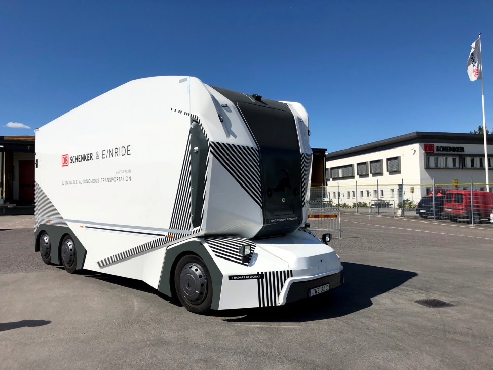 Einride's white autonomous electric truck with black geometric patterns parked outside industrial building