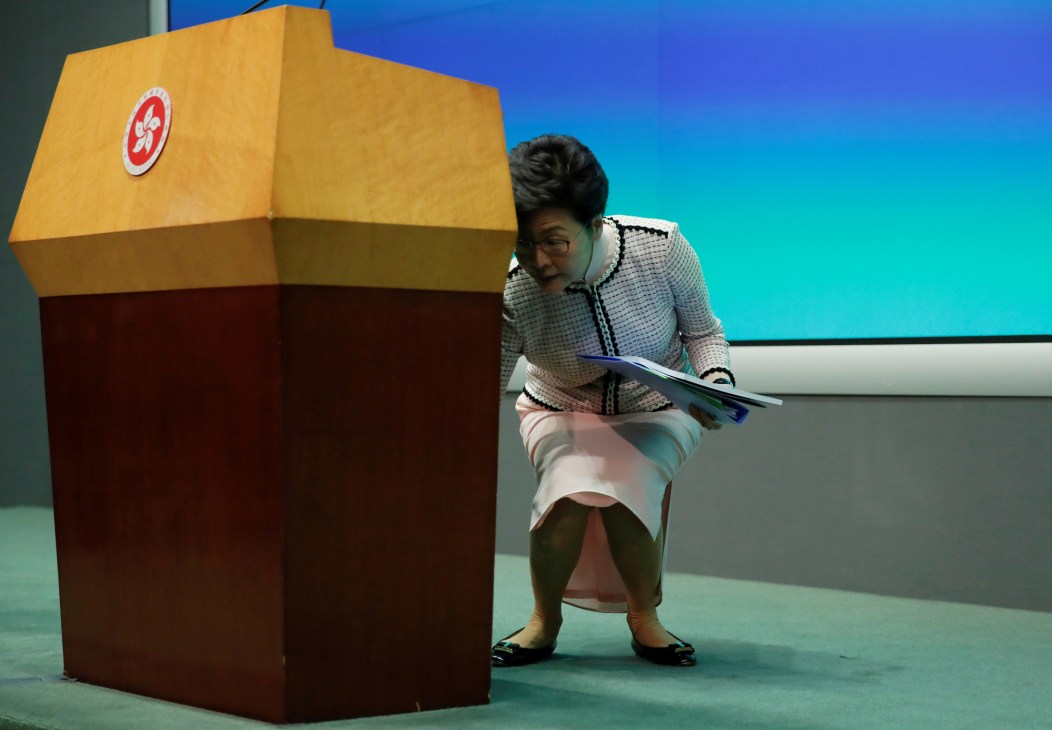 Hong Kong's chief executive Carrie Lam sits at a voting booth bearing the Hong Kong emblem during an election.