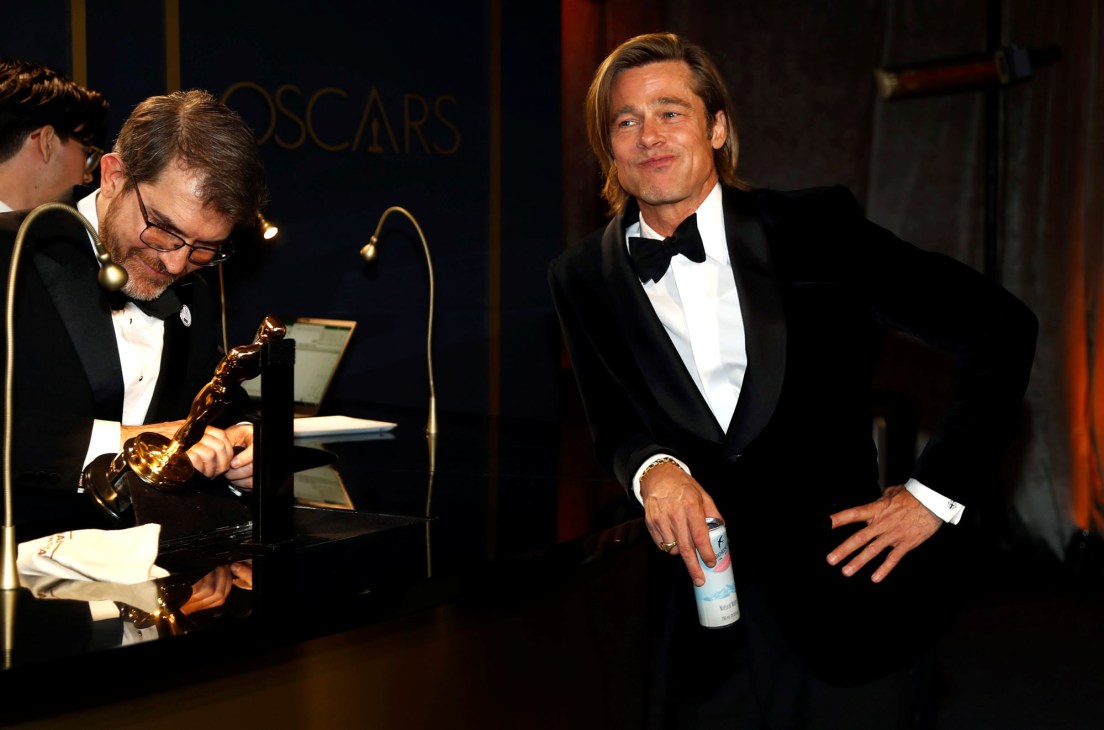 Brad Pitt in black tuxedo holding Oscar statue at awards ceremony