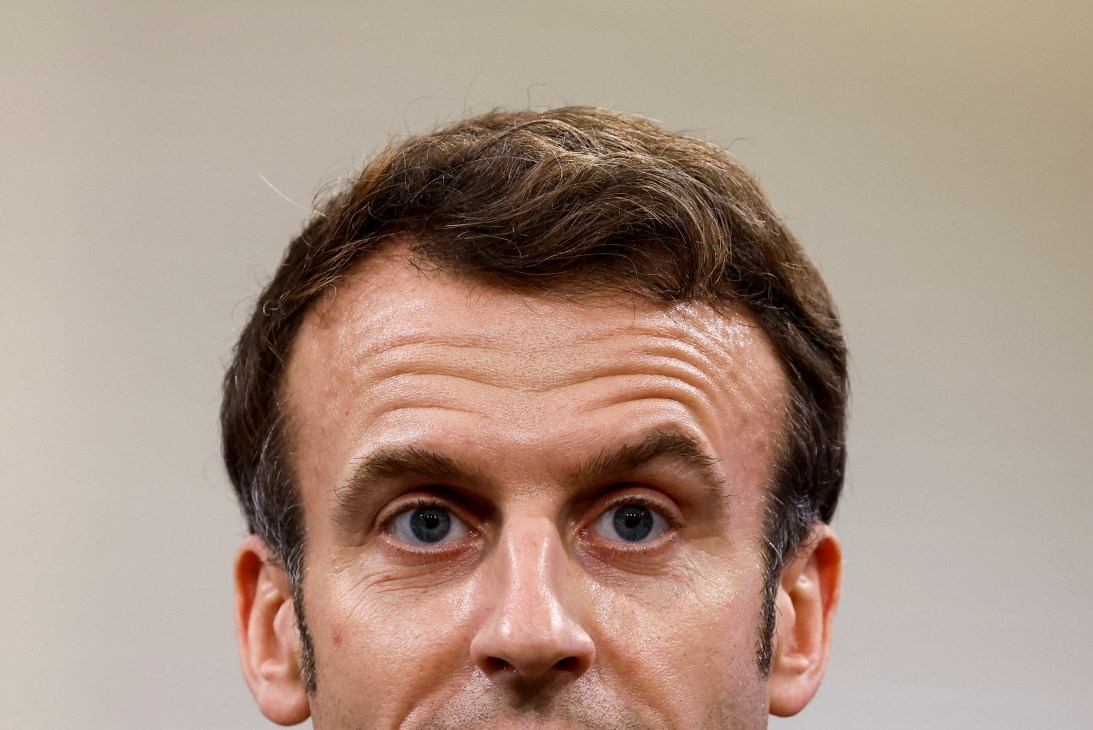 Close-up portrait of Emmanuel Macron looking directly at camera with raised eyebrows and intense expression