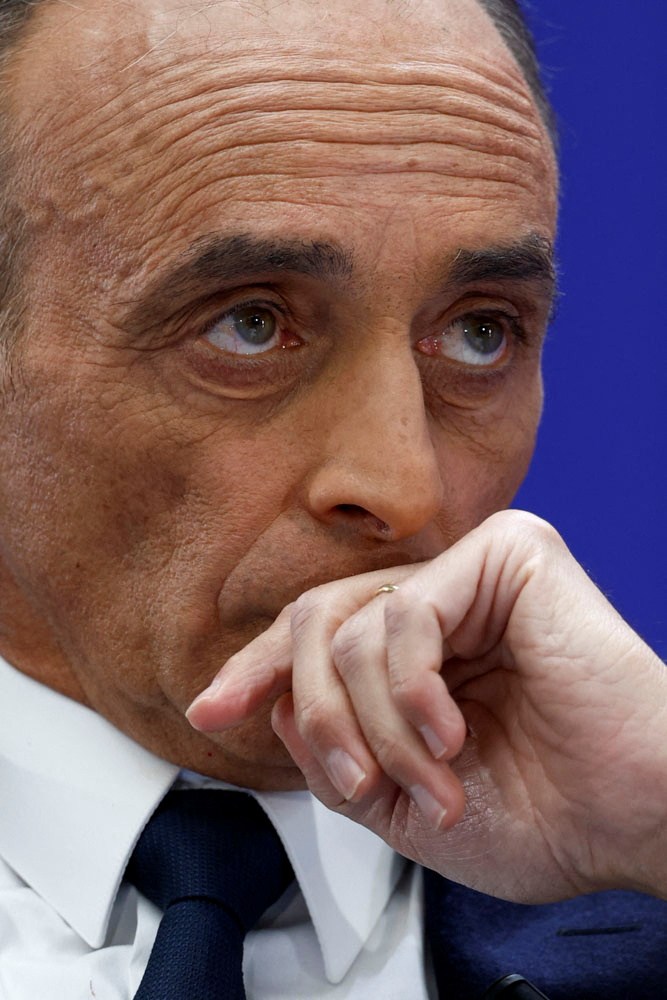 Close-up of an older man in a suit and tie with his hand thoughtfully positioned near his mouth