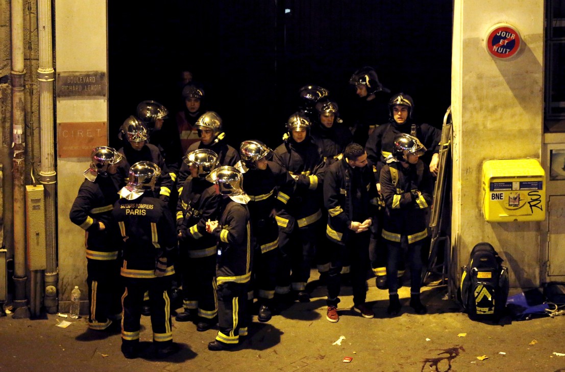 Firefighters in protective gear and helmets gathered on a street at night during emergency response