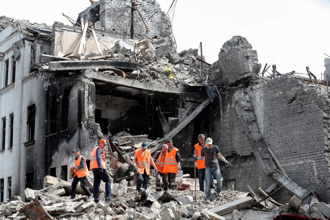 Search and rescue workers in high-visibility vests working through rubble and debris of a destroyed building