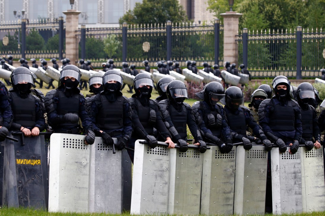 Riot police in full protective gear with shields standing in formation during a Belarus opposition demonstration.