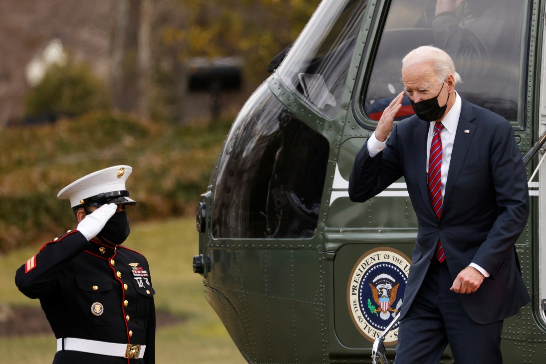 Biden saluting while exiting Marine One helicopter with military guard saluting nearby