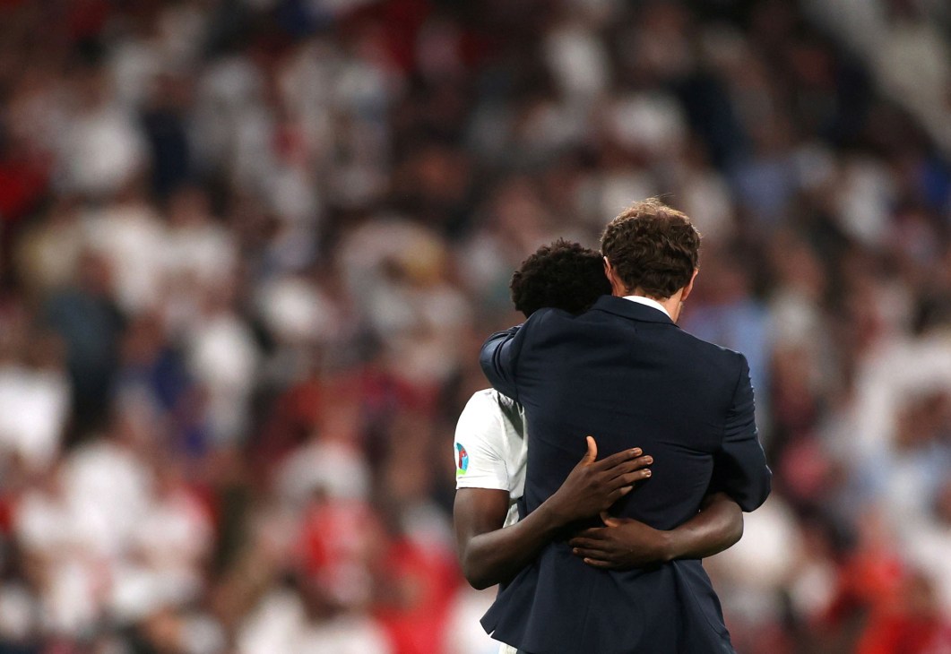 Two men in England football shirts embracing in disappointment after Euro 2020 final defeat