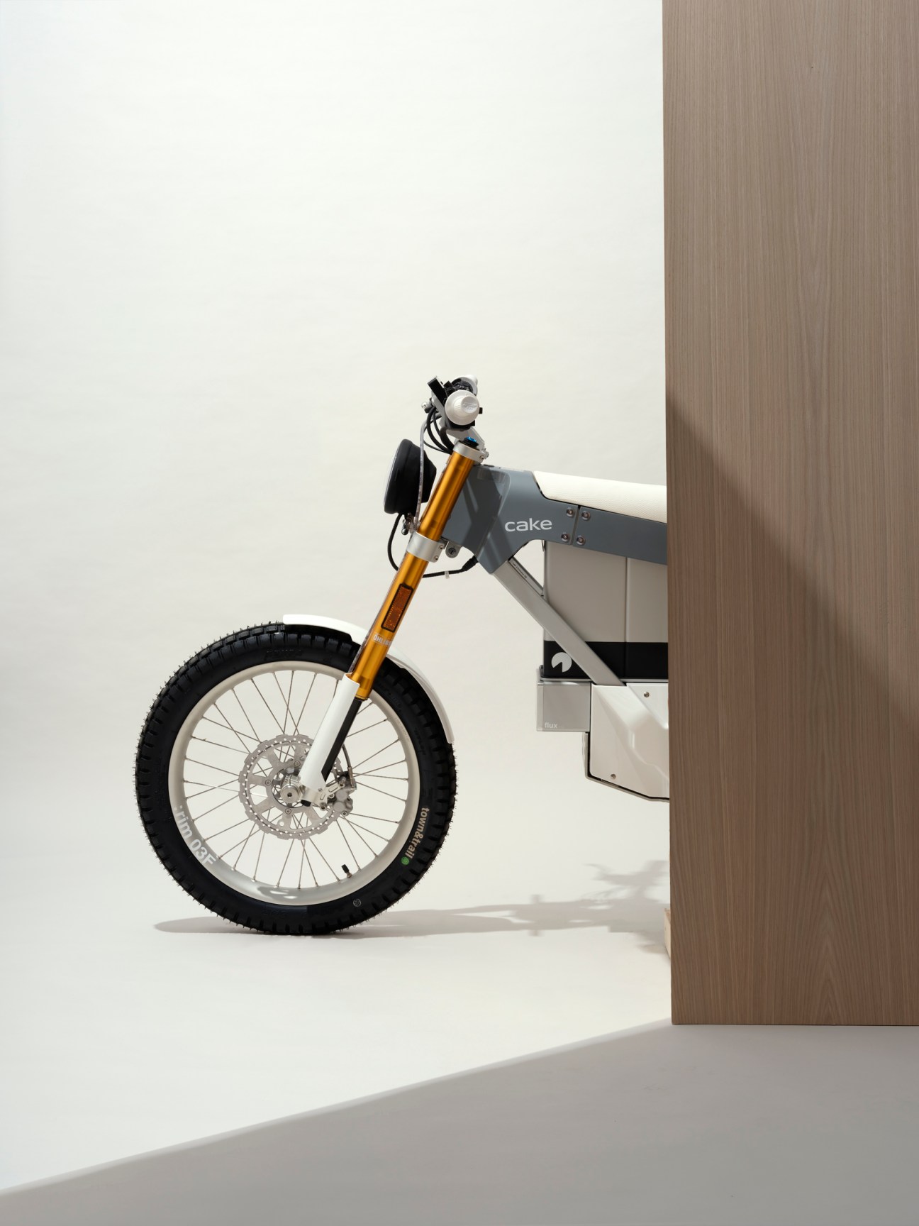 Cake Kalk & electric motorcycle with orange front fork and gray frame displayed in minimalist white interior