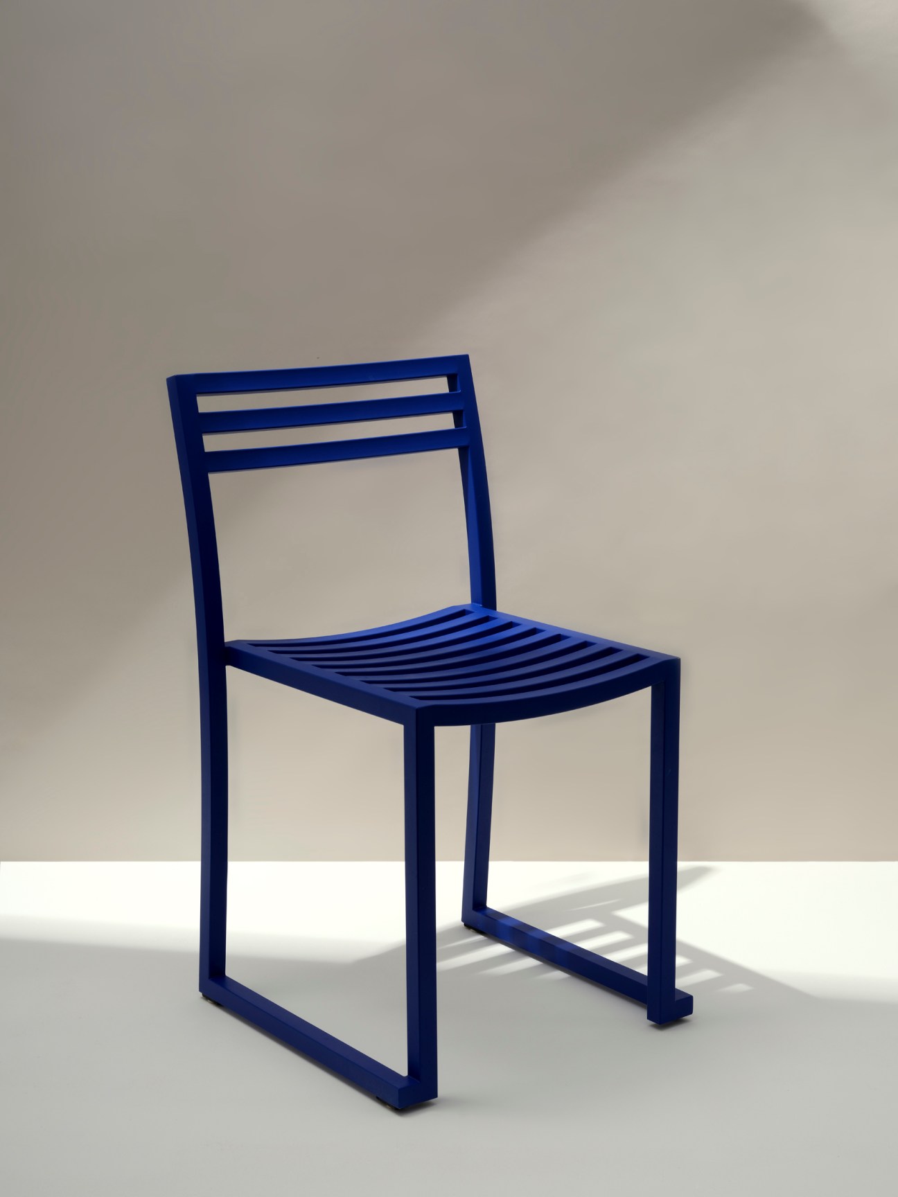Blue metal outdoor chair with slatted seat and back in minimalist design