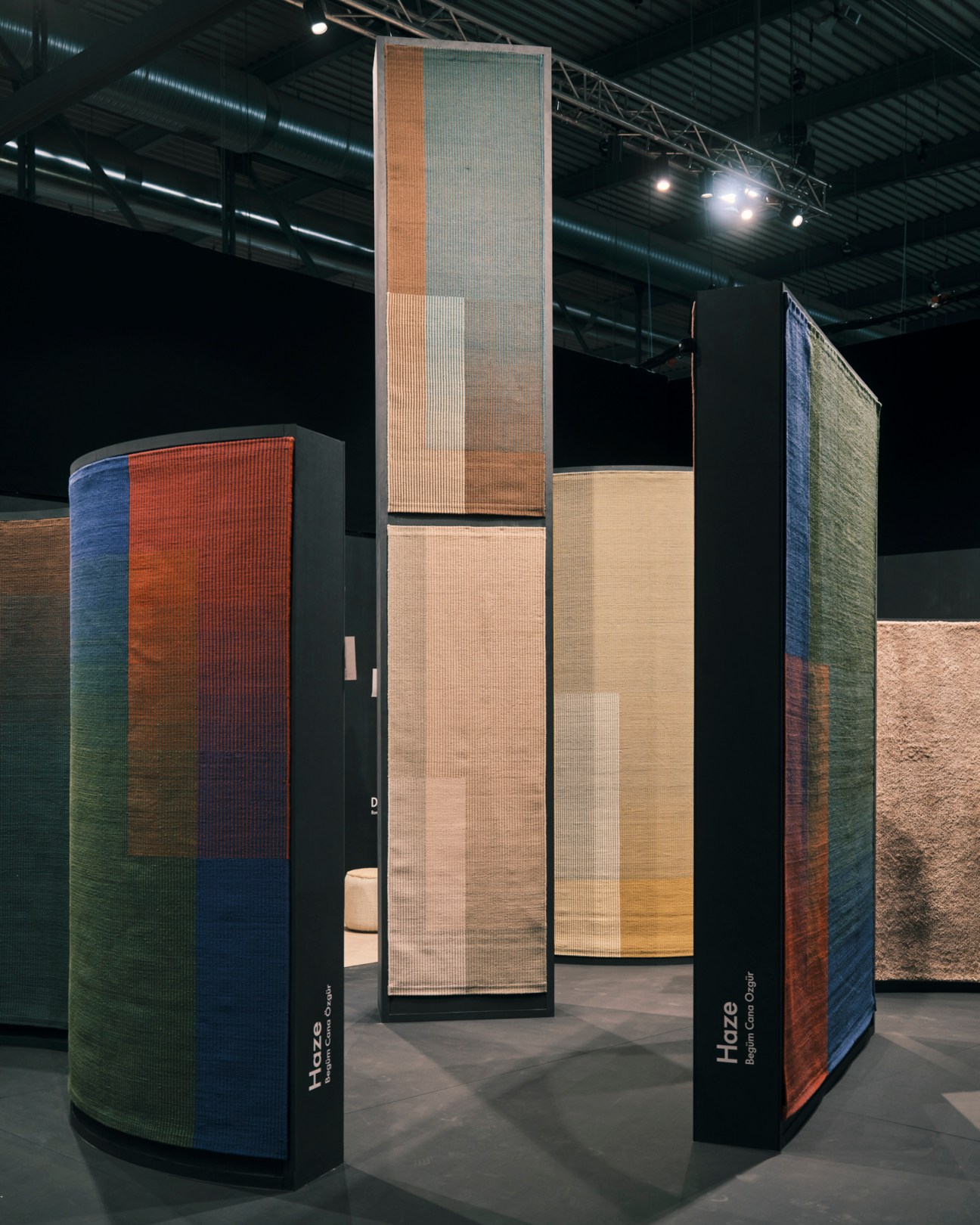 Tall vertical rug displays showing Haze collection by Nanimarquina with gradient wool colors at furniture fair