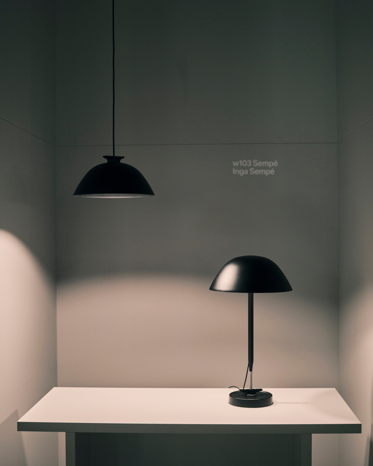 W103 Sempé desk lamp by Wästberg with black dome shade and adjustable arm on white surface