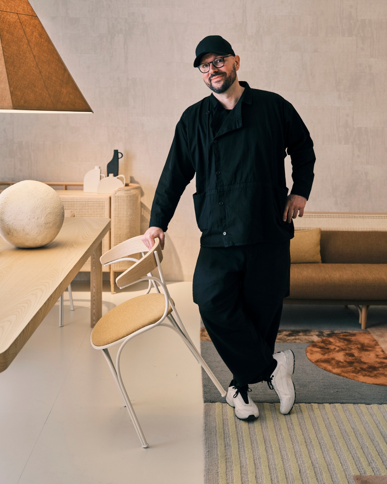 Luca Nichetto standing next to a curved metal chair in a modern showroom setting