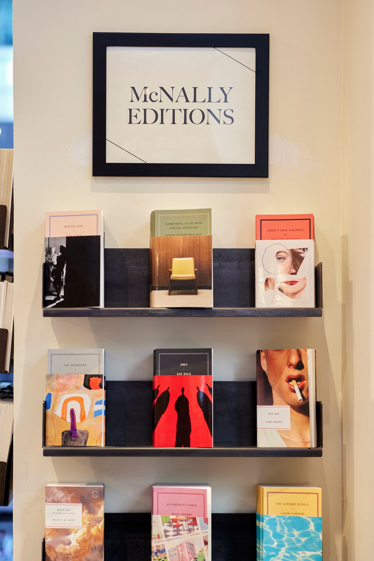 Display of books from McNally Editions publishing arm on wooden bookstore shelving