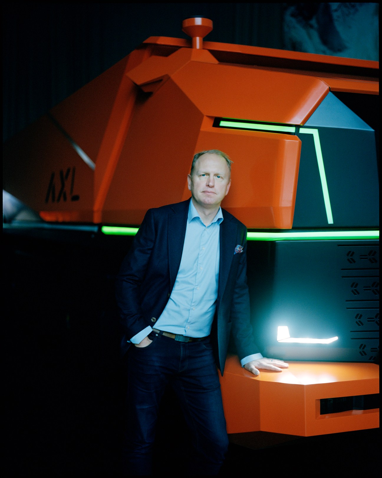 Henrik Henriksson in business attire standing in front of orange industrial machinery