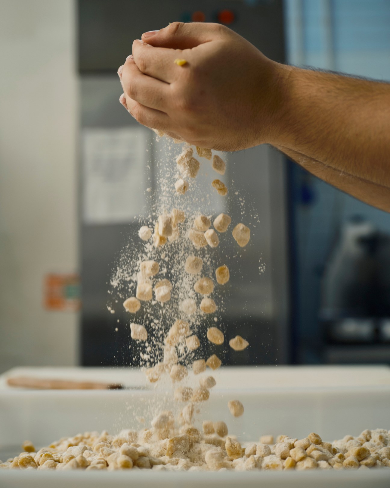 A hand crumbles struffoli dough pieces over a work surface at Scaturchio pastry shop.
