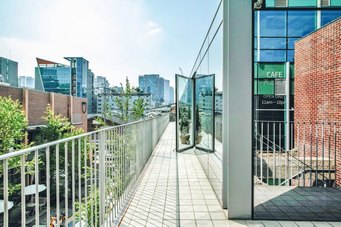 Rooftop terrace of Seongsu Yeonbang with café entrance, plants, and Seoul skyline view.
