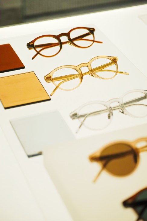 Multiple eyeglass frames in tortoiseshell, gold, and clear acetate displayed on a white surface with colored swatches.