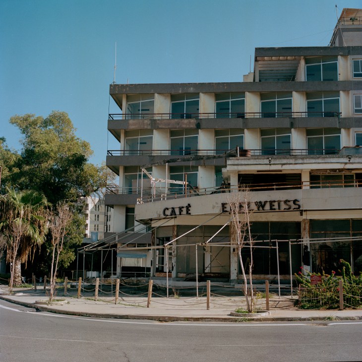 Modernist concrete hotel building with multiple floors of balconies and large windows, showing signs of decay