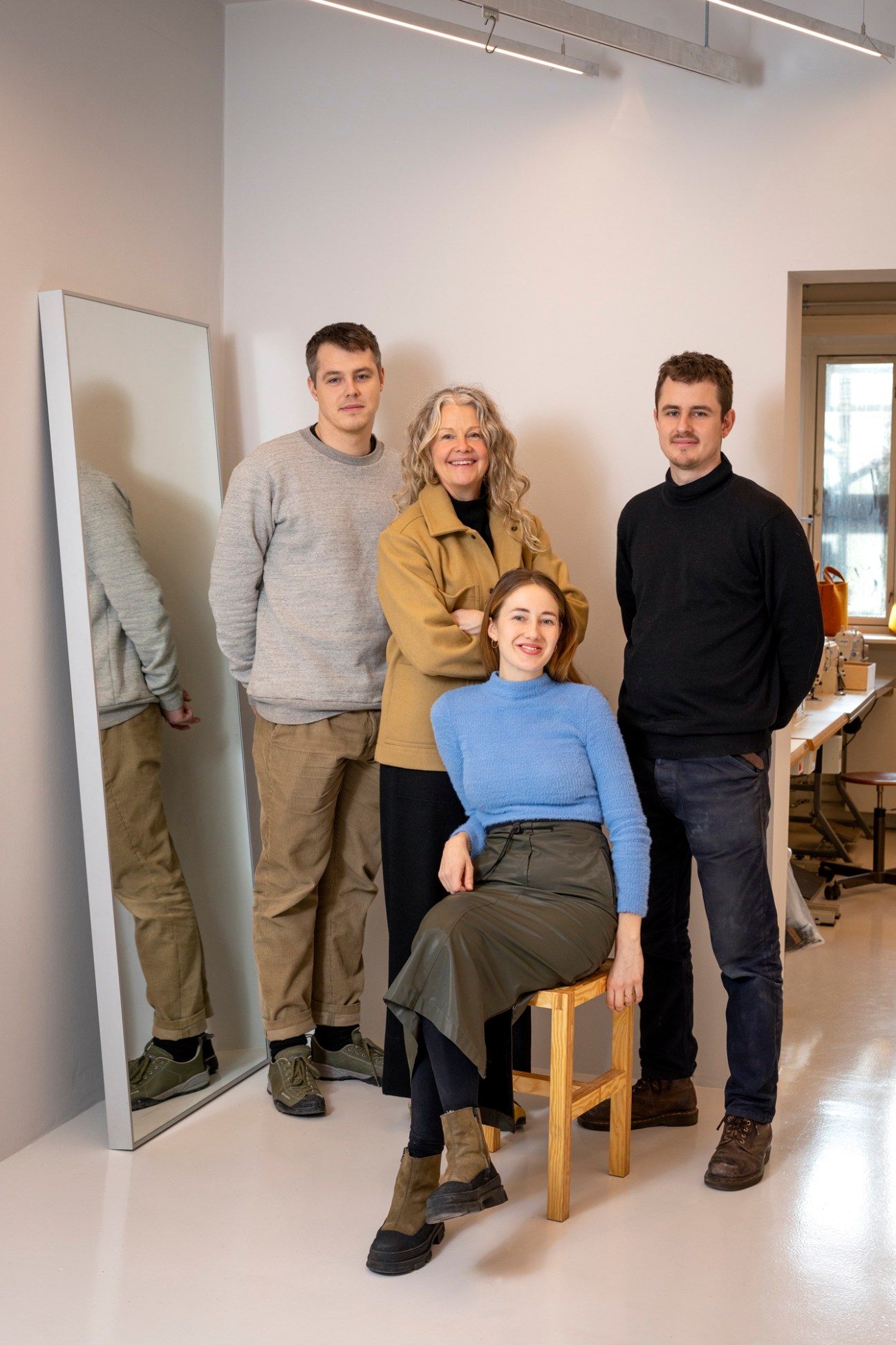 Four people posing together in a bright retail space with concrete floors and white walls
