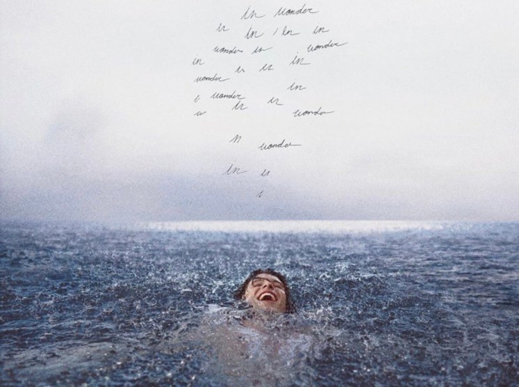 Person swimming joyfully in ocean water with handwritten text scattered above