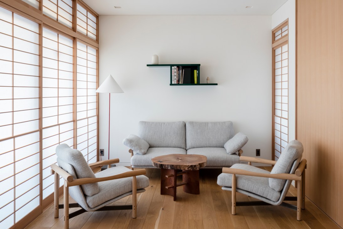 Modern hotel lounge with gray furniture, wooden coffee table, and traditional Japanese shoji screens