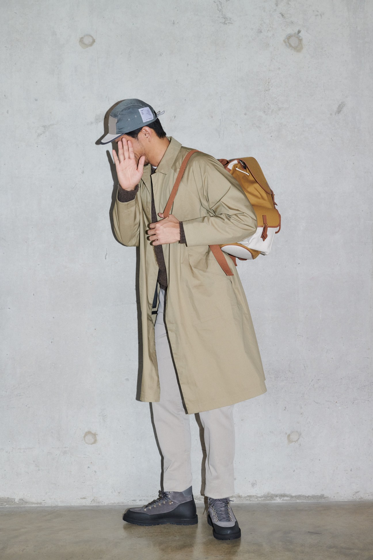 Man in technical coat with multiple layers, boots and cap in sporty styling