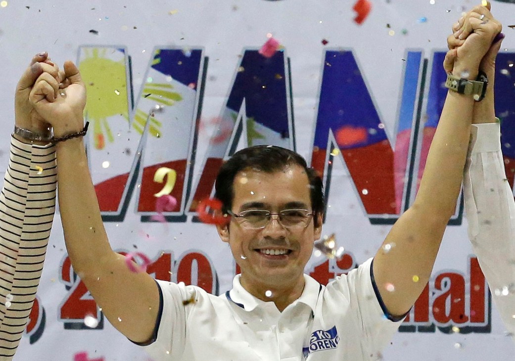 Isko Moreno celebrating with raised arms amid confetti, wearing glasses and white polo shirt