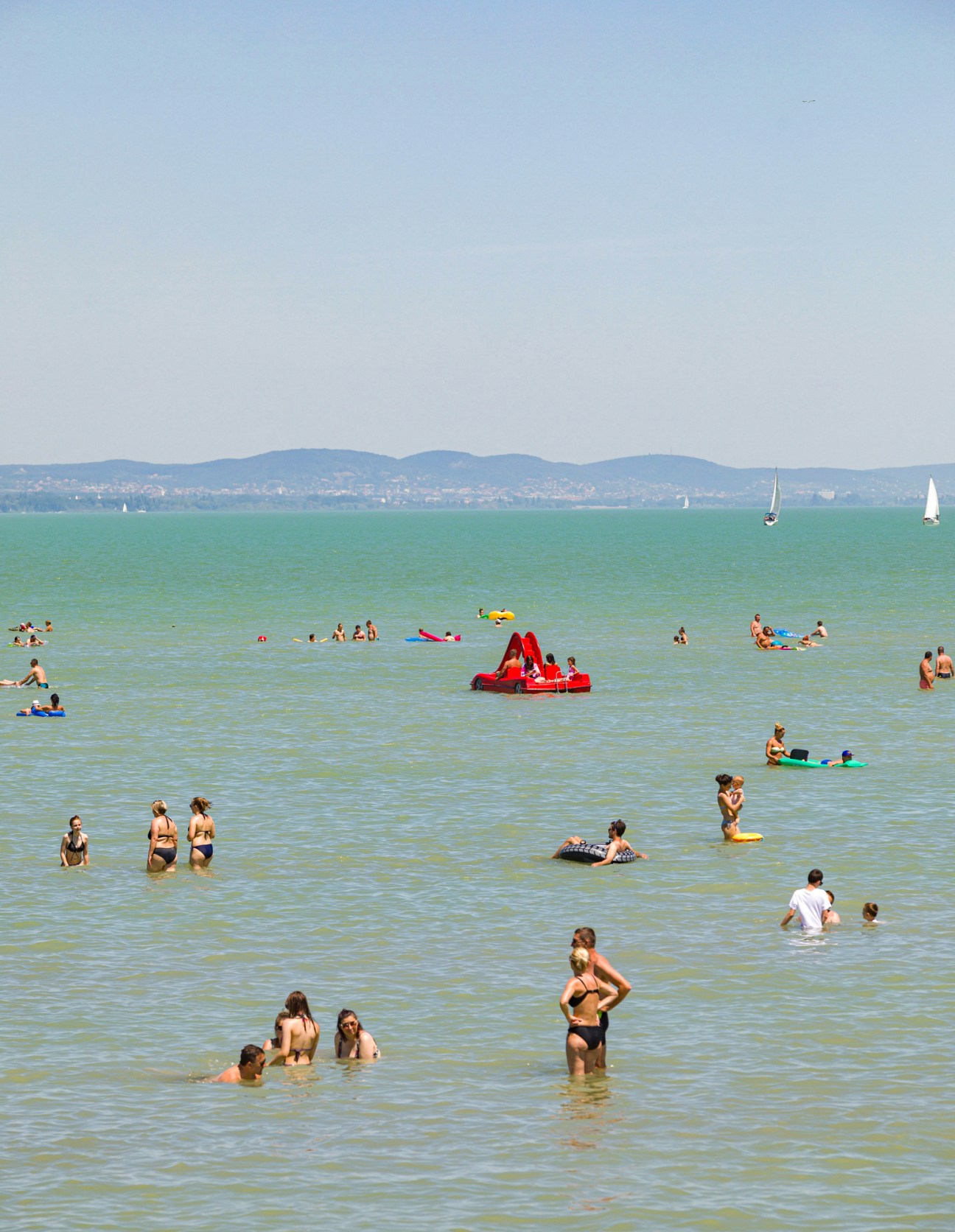 Boats and yachts on Lake Balaton with shoreline and hills in background
