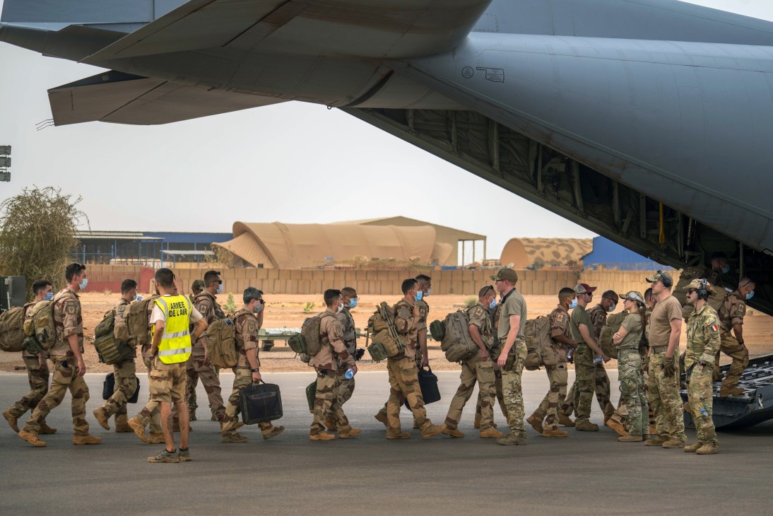 Soldiers in military fatigues boarding or disembarking from an aircraft on an airfield
