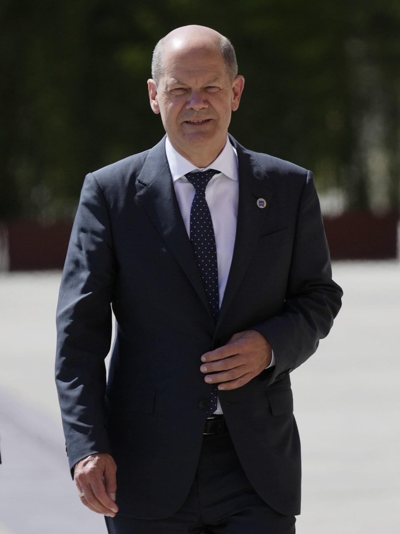 Olaf Scholz in a dark business suit walking outdoors