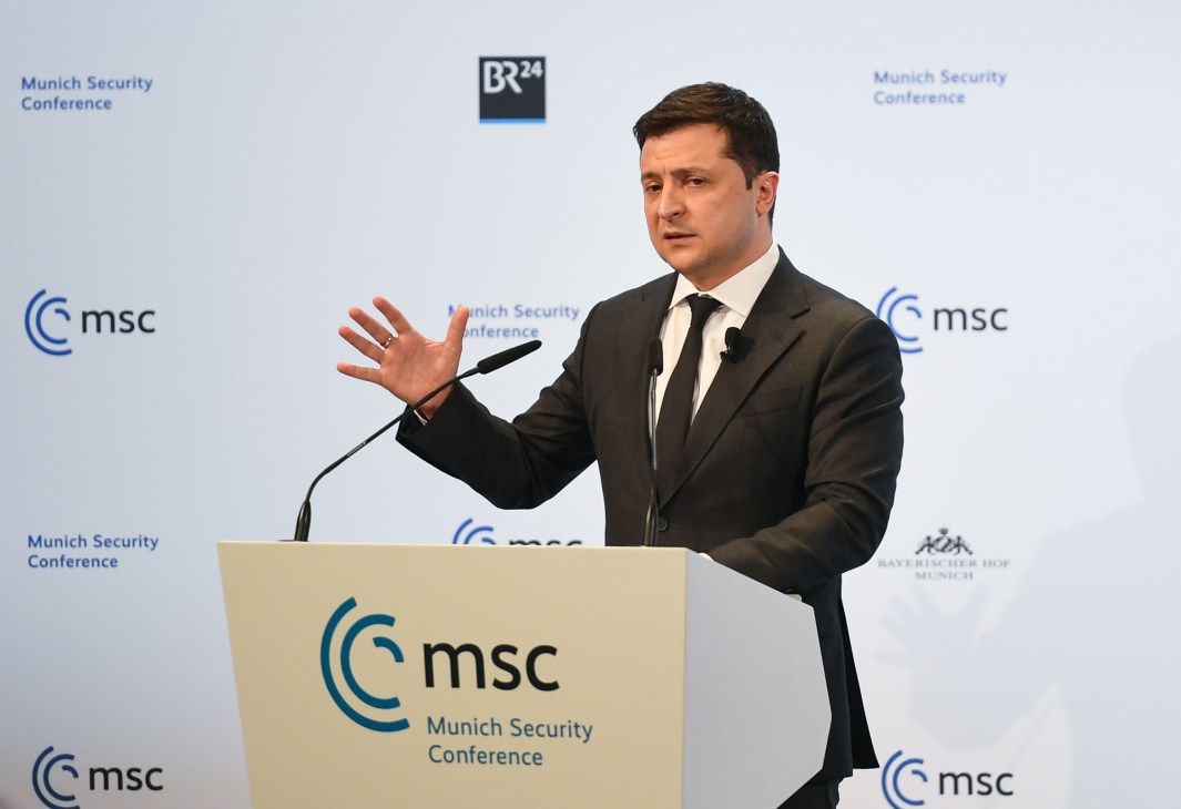 Man in dark suit speaking at Munich Security Conference podium with gesture.