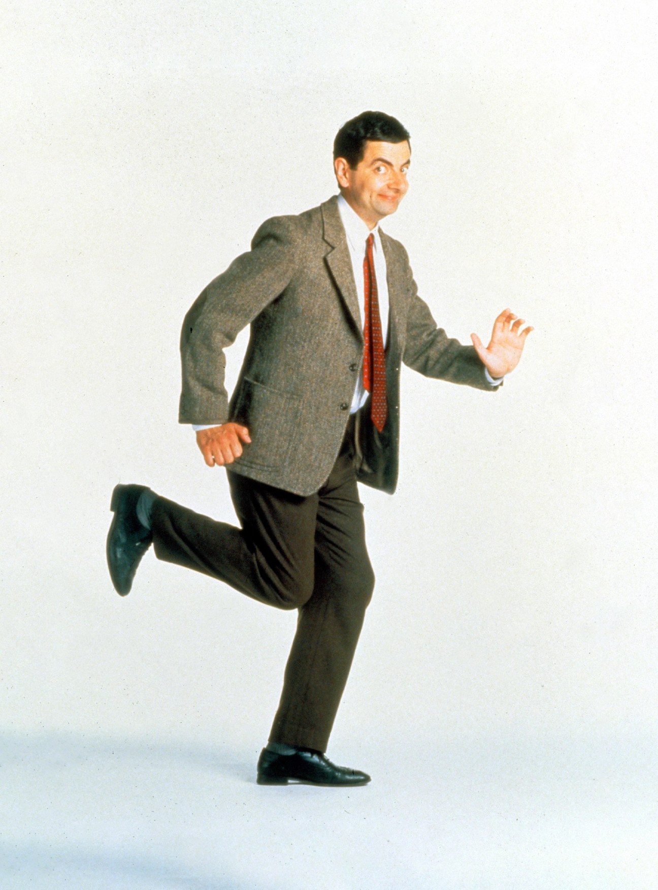 Man in gray suit character Mr Bean and red tie running with exaggerated facial expression