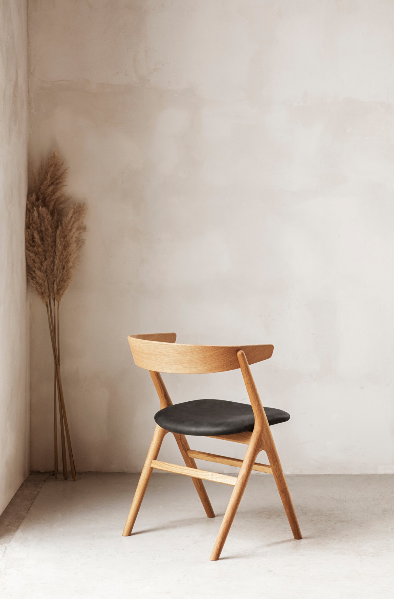 Sibast No 9 chair with solid oak frame, curved backrest and black leather seat in minimalist interior.