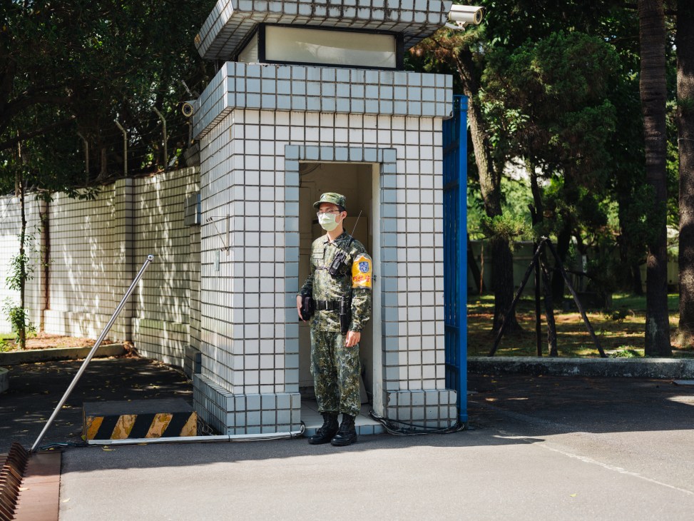 Armed sentry in military fatigues stands guard at the entrance of the INDSR think-tank compound in Taipei.