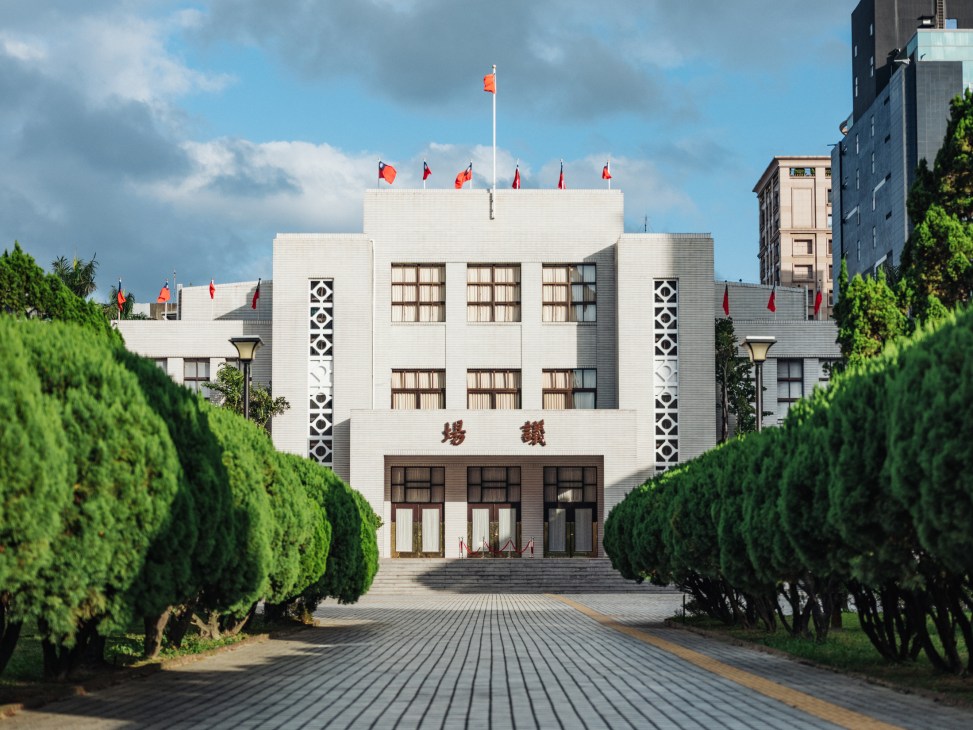 Taiwan's Legislative Yuan parliament building with white facade and red flags on the roof.