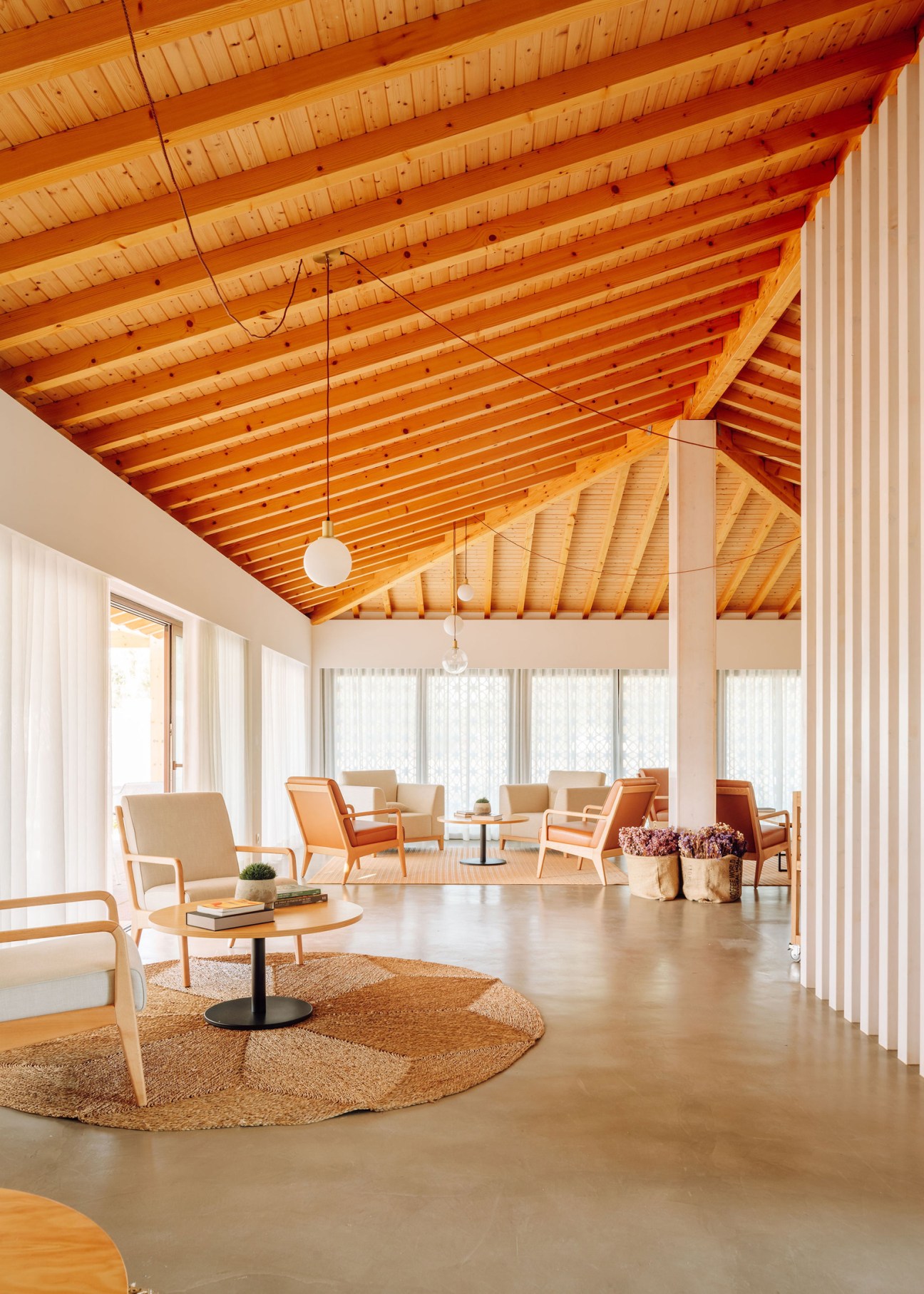 Modern hotel interior with exposed wood beam ceiling, contemporary furniture, and large windows with natural light