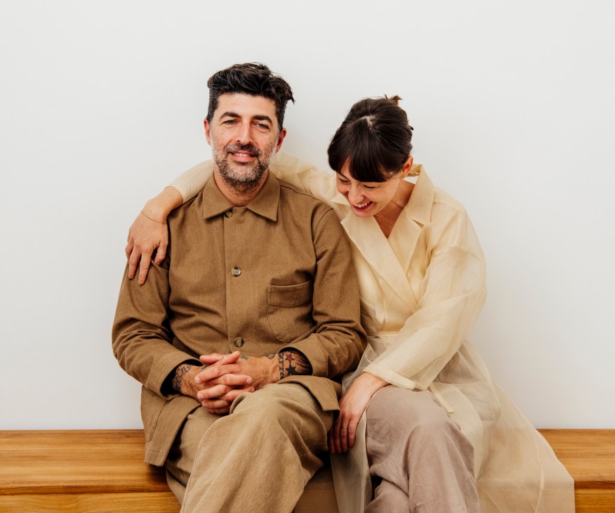 Husband and wife Frank Agostino and Rhianna Tycholis, co-owners of Mixed Business, sitting together wearing neutral-toned clothing.