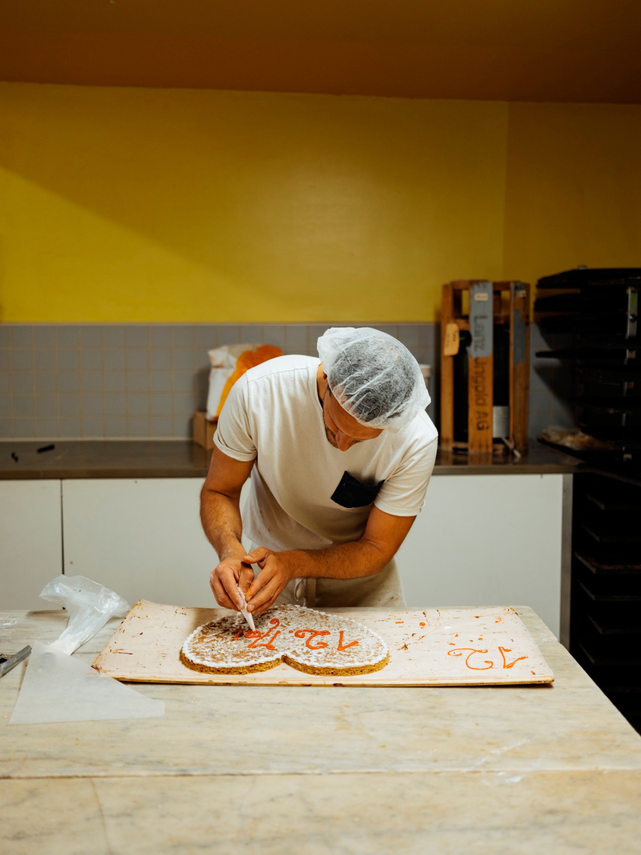A baker decorating a cookie with icing.