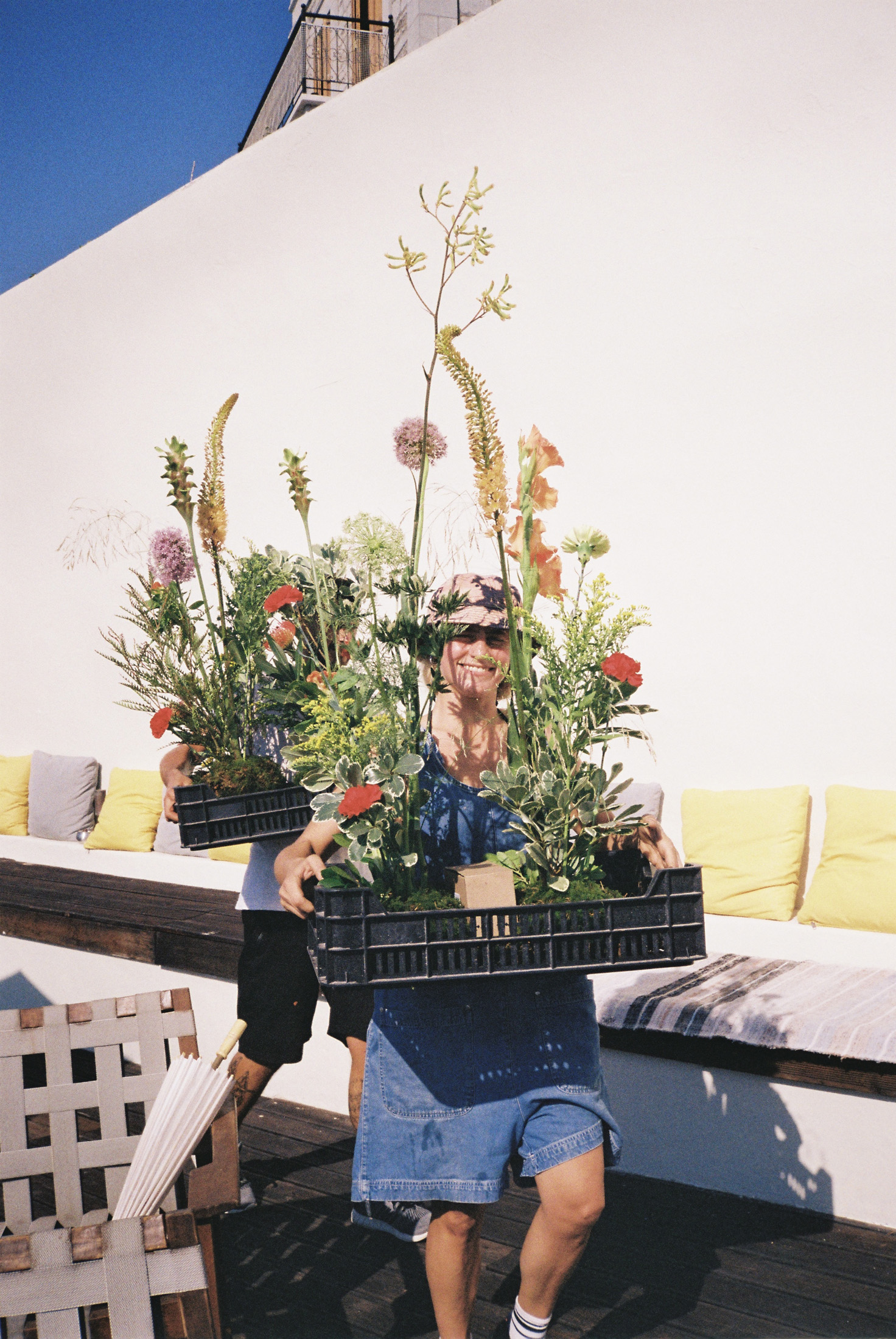 A woman carrying a plastic tray of plants.