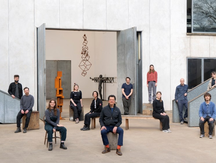 Group of people posing in an open sculpture studio with their works.