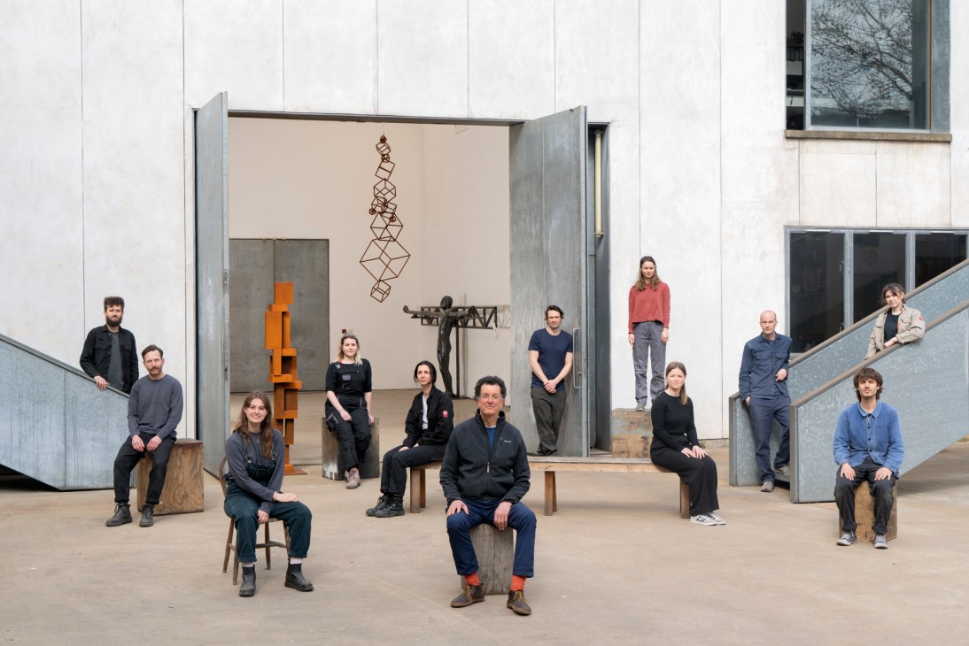 Group photo of Antony Gormley's 11-person London studio team posing in their modern workshop space