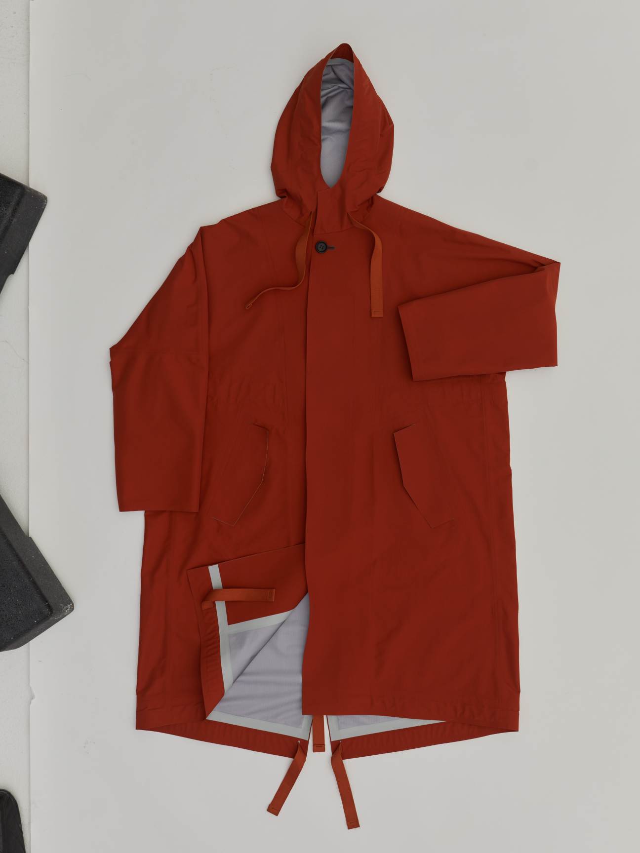 Red hooded coat with belt ties and white lining displayed against white background