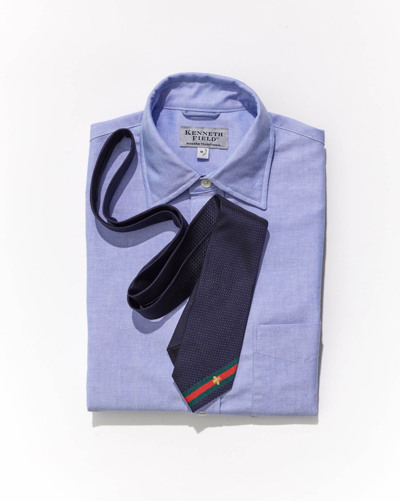 Navy tie with red and green stripe detail by Gucci draped over light blue Kenneth Field dress shirt